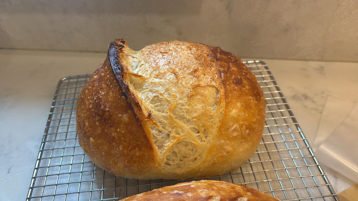 Finished sourdough loaf cooling on rack